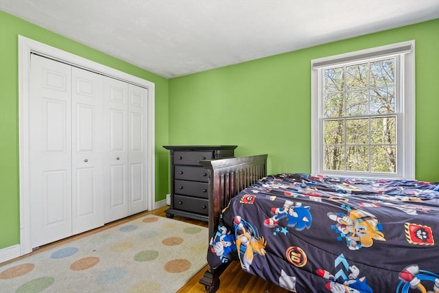 bedroom with baseboards, wood finished floors, and a closet