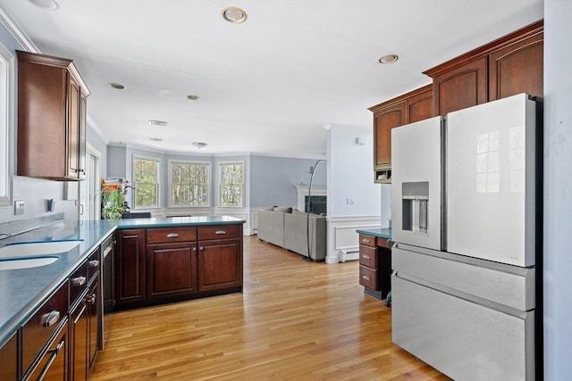 kitchen with white refrigerator with ice dispenser, a sink, a peninsula, open floor plan, and light wood-style floors