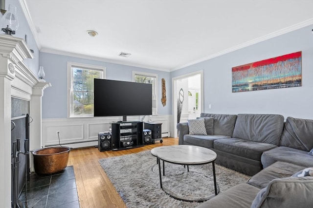 living room with crown molding, baseboard heating, visible vents, and wood finished floors