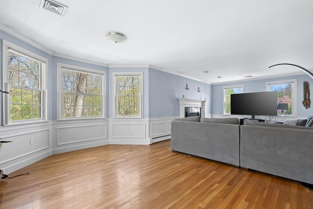 living room with visible vents, ornamental molding, baseboard heating, and light wood-type flooring