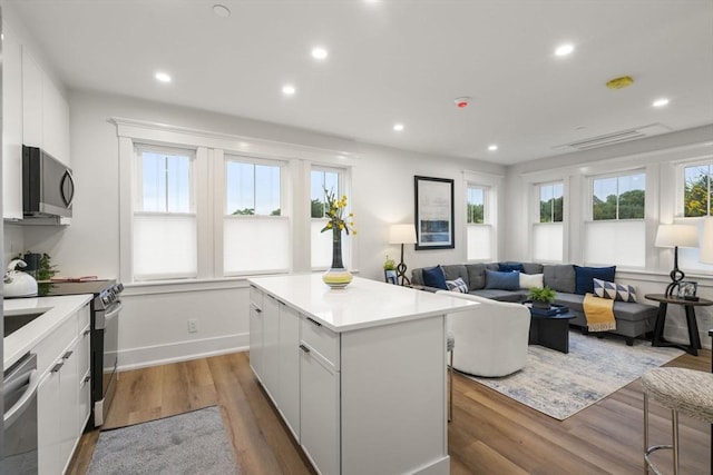 kitchen with white cabinets, a center island, light hardwood / wood-style floors, and stainless steel appliances