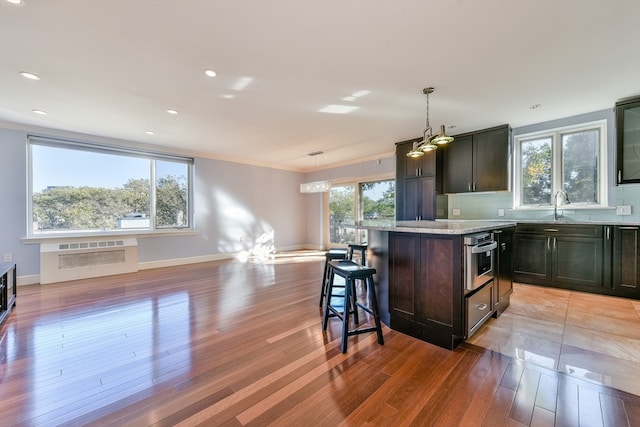 kitchen featuring light hardwood / wood-style flooring, a breakfast bar area, decorative light fixtures, and a kitchen island