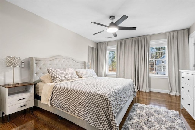 bedroom featuring ceiling fan, dark wood-type flooring, multiple windows, and baseboards