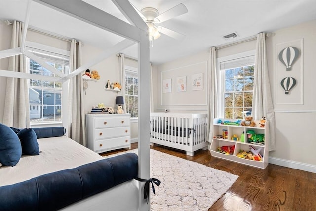 bedroom with baseboards, multiple windows, visible vents, and wood finished floors