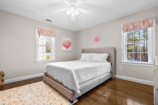 bedroom featuring ceiling fan, wood finished floors, visible vents, and baseboards