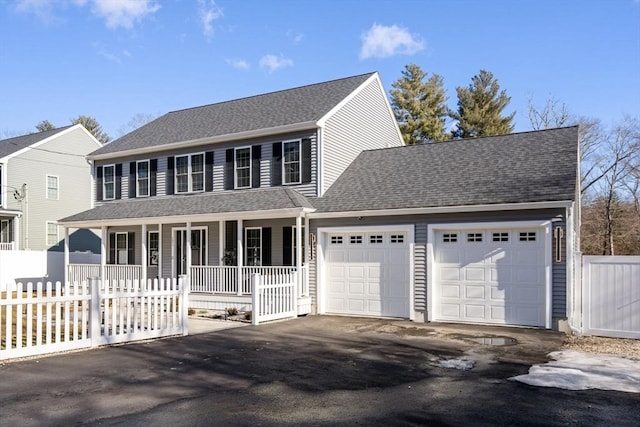 colonial house featuring a garage, aphalt driveway, roof with shingles, fence, and a porch