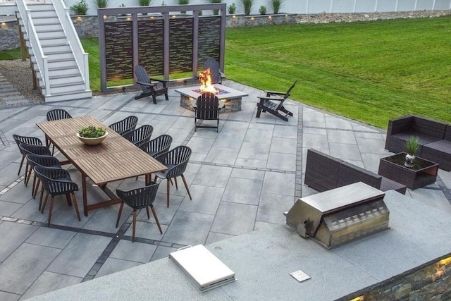 view of patio with outdoor dining area, an outdoor living space with a fire pit, and stairs