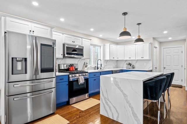 kitchen with dark wood-style floors, blue cabinets, a sink, stainless steel appliances, and backsplash