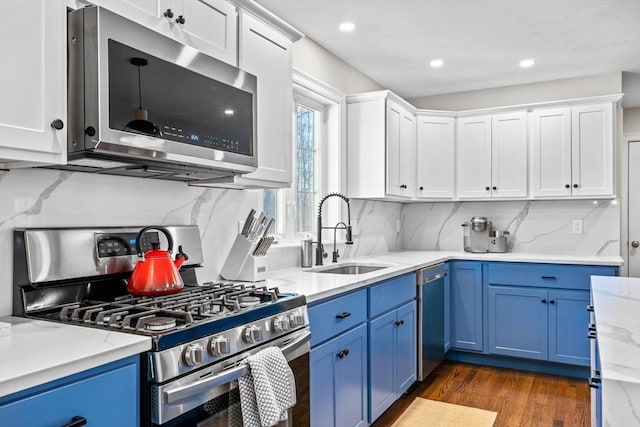 kitchen with blue cabinetry, white cabinetry, stainless steel appliances, and a sink