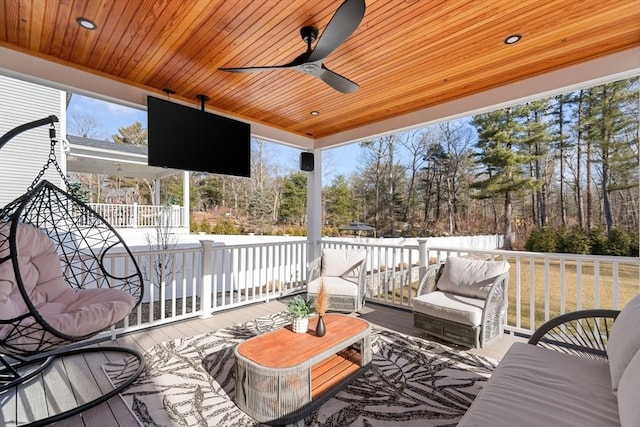 wooden deck with outdoor lounge area and a ceiling fan