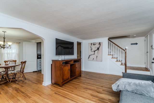 interior space with a chandelier, a textured ceiling, light hardwood / wood-style floors, and crown molding