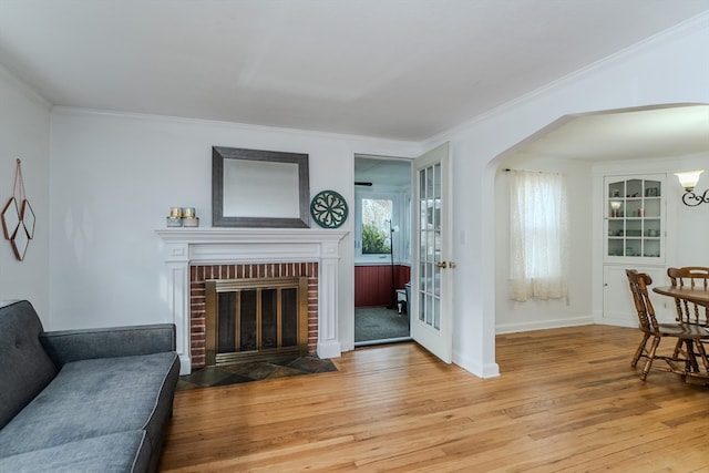 living room featuring a fireplace, light wood-type flooring, and crown molding