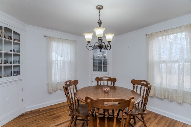 dining space featuring ornamental molding, hardwood / wood-style flooring, and a notable chandelier