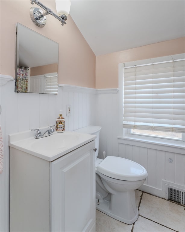 bathroom with tile patterned flooring, vanity, toilet, and vaulted ceiling