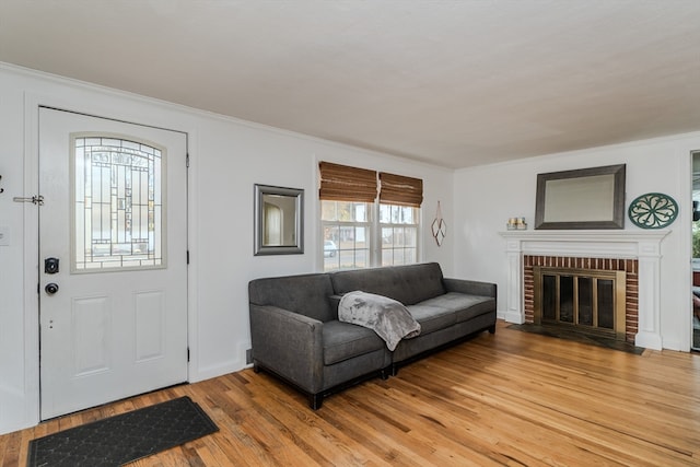 living room with light wood-type flooring, a fireplace, and ornamental molding