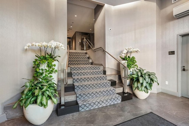 stairway with marble finish floor, a wall mounted AC, and baseboards