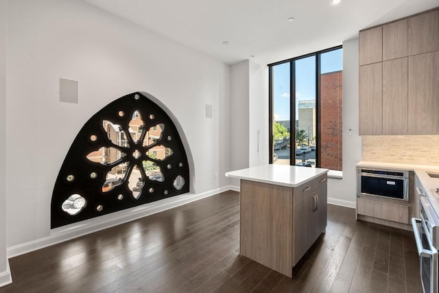 kitchen with modern cabinets, a kitchen island, dark wood-type flooring, a wall of windows, and light countertops