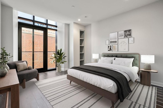 bedroom featuring expansive windows, recessed lighting, baseboards, and wood finished floors