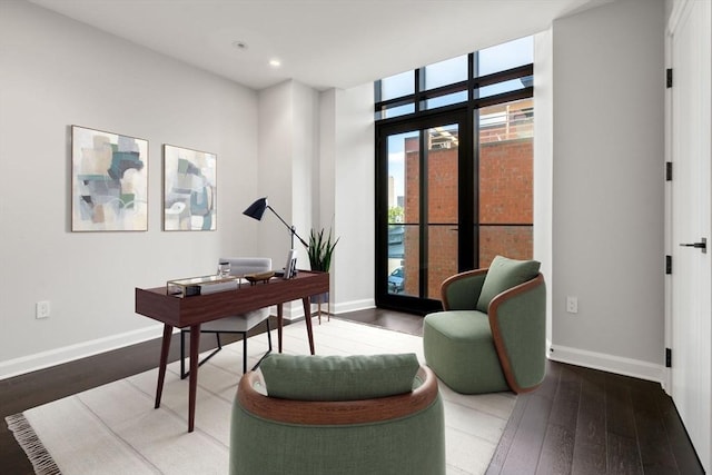 office space featuring a wall of windows, recessed lighting, hardwood / wood-style flooring, and baseboards