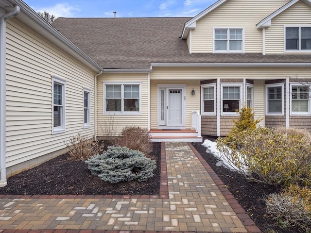 doorway to property with roof with shingles