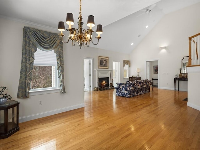 living room with high vaulted ceiling, baseboards, light wood-style floors, a lit fireplace, and stairway