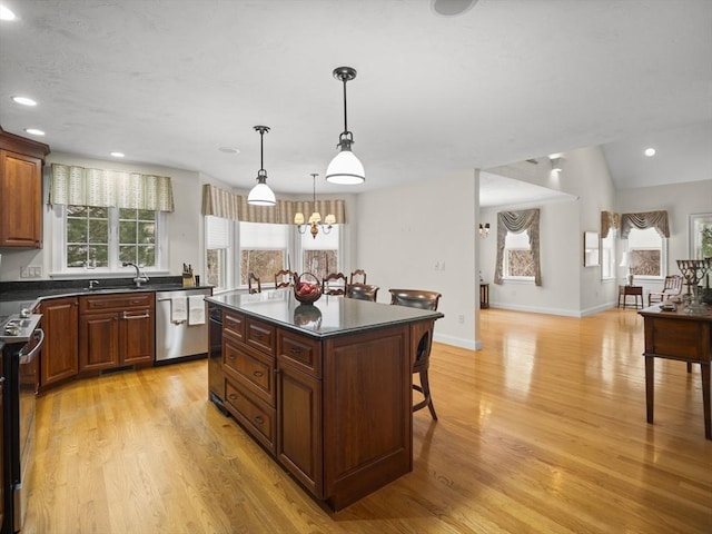 kitchen featuring light wood finished floors, dishwasher, electric stove, dark countertops, and a breakfast bar