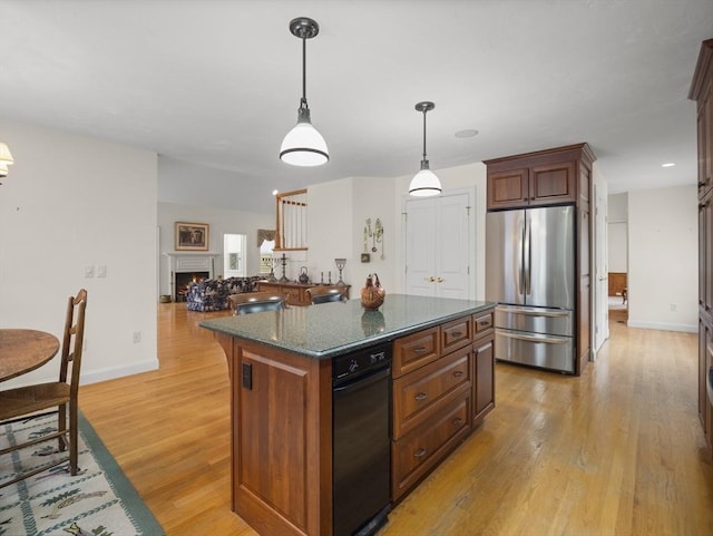 kitchen with a warm lit fireplace, light wood-style flooring, a kitchen island, freestanding refrigerator, and hanging light fixtures