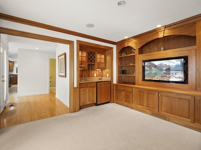 interior space with crown molding, light colored carpet, a sink, wet bar, and baseboards