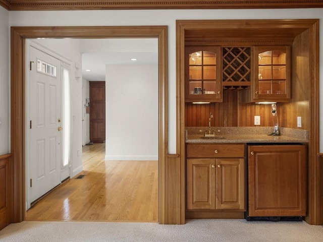 bar with light wood-type flooring, indoor wet bar, a sink, and visible vents