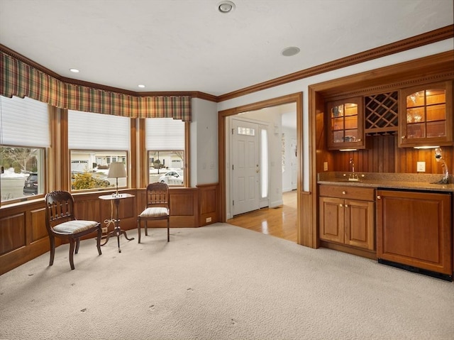 sitting room featuring indoor wet bar, recessed lighting, ornamental molding, wainscoting, and light carpet