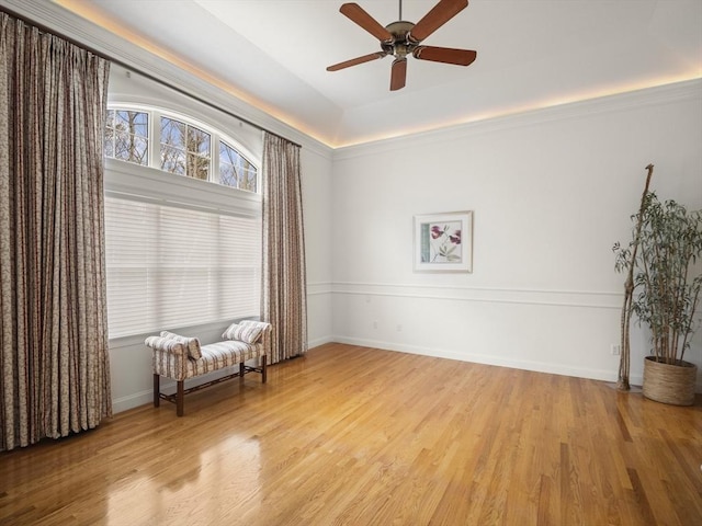 living area with light wood-type flooring, a ceiling fan, and baseboards