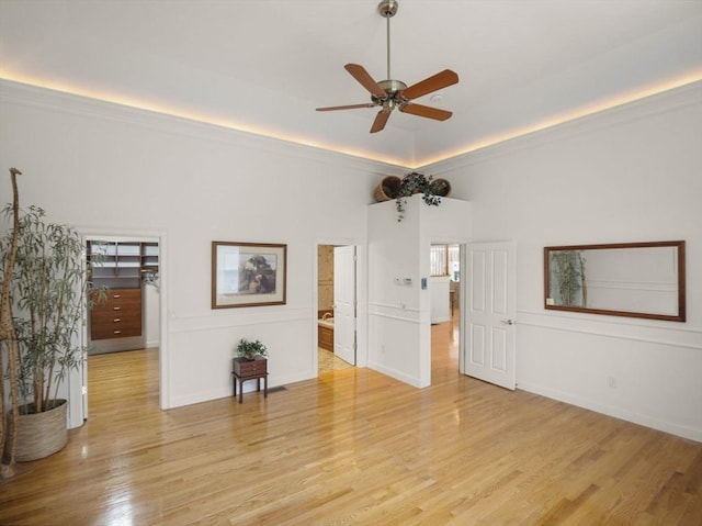 unfurnished room with light wood finished floors, ornamental molding, and a ceiling fan