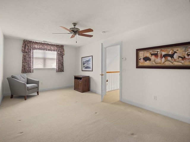 living area featuring light carpet, baseboards, and a ceiling fan