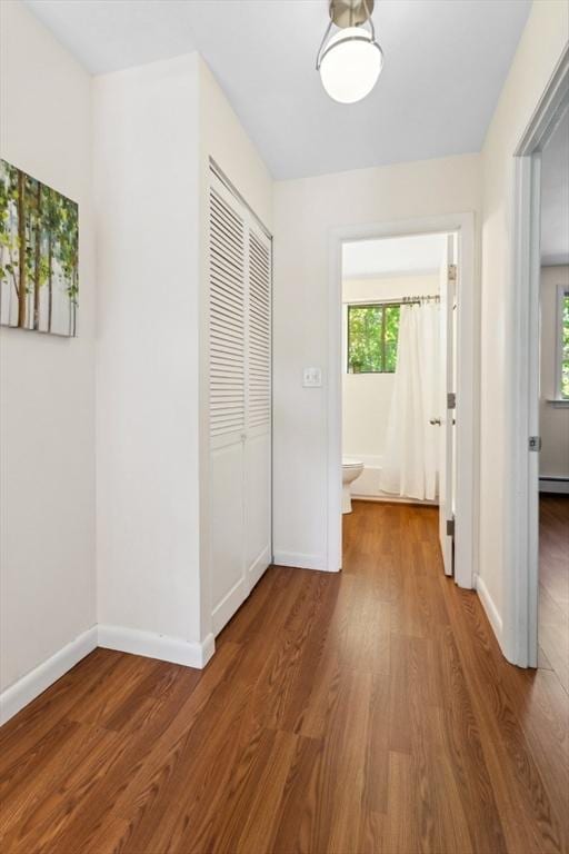 hallway with wood finished floors, plenty of natural light, and baseboards