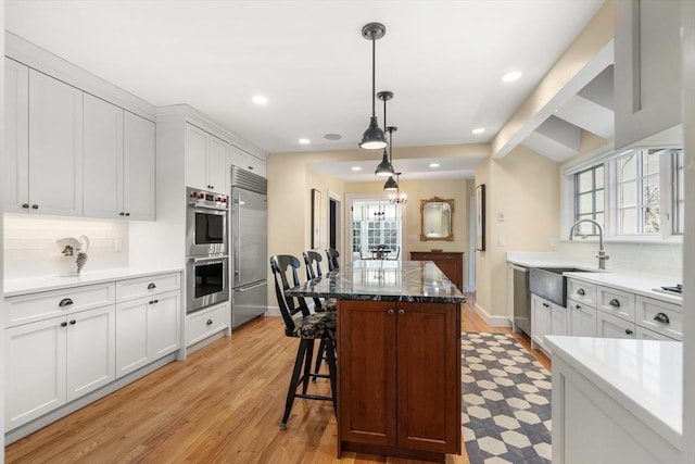 kitchen with hanging light fixtures, white cabinetry, appliances with stainless steel finishes, and sink