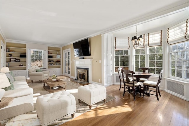 living room with hardwood / wood-style flooring, ornamental molding, and an inviting chandelier