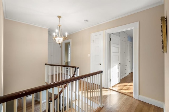 corridor with ornamental molding, a chandelier, and light hardwood / wood-style flooring