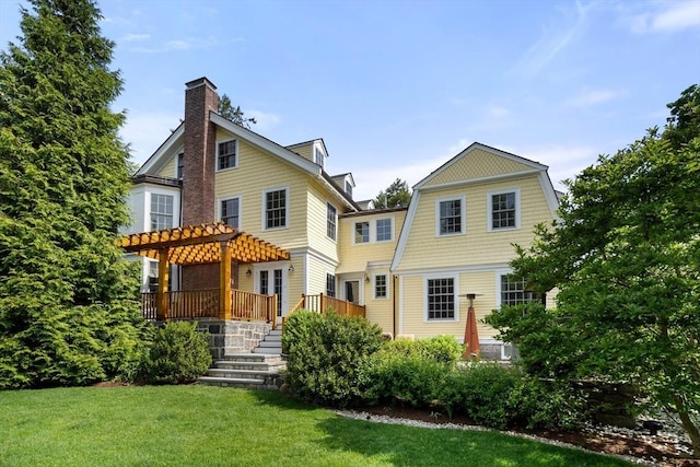 rear view of property featuring a yard, a pergola, and a deck