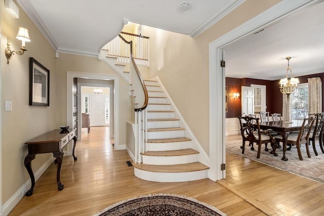 stairway with an inviting chandelier, ornamental molding, and hardwood / wood-style flooring