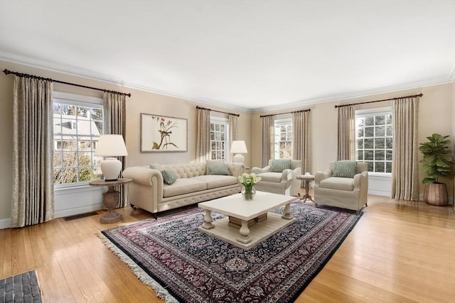 living room featuring crown molding, a healthy amount of sunlight, and light hardwood / wood-style floors