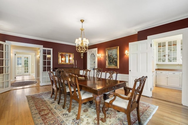 dining space featuring an inviting chandelier, crown molding, and light hardwood / wood-style flooring