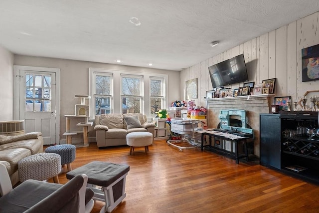 living room with wood-type flooring, a stone fireplace, and a wealth of natural light