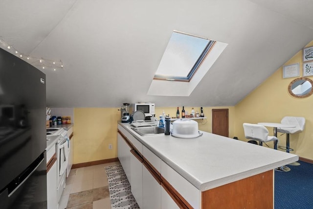 kitchen with white appliances, lofted ceiling with skylight, sink, and white cabinets