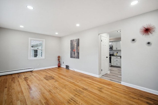 spare room with light wood-type flooring and a baseboard heating unit