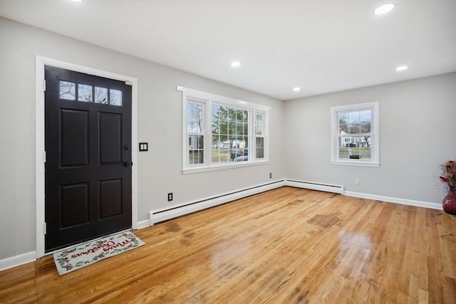 foyer with a baseboard heating unit, light hardwood / wood-style floors, and a healthy amount of sunlight