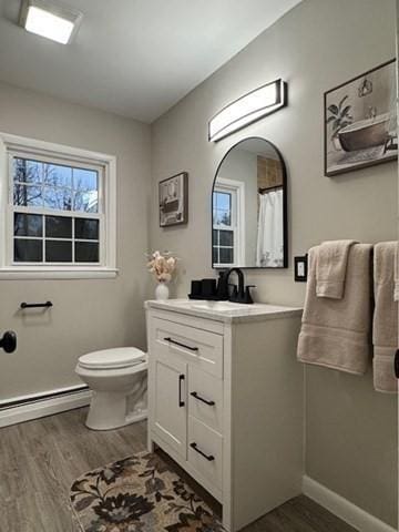 bathroom featuring a shower with shower curtain, vanity, baseboard heating, hardwood / wood-style flooring, and toilet