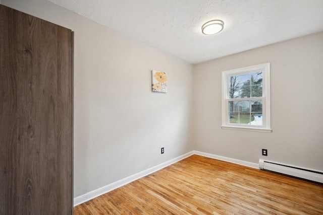 unfurnished room featuring light wood-type flooring and a baseboard radiator