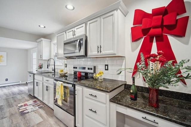 kitchen with sink, light hardwood / wood-style flooring, appliances with stainless steel finishes, tasteful backsplash, and white cabinetry