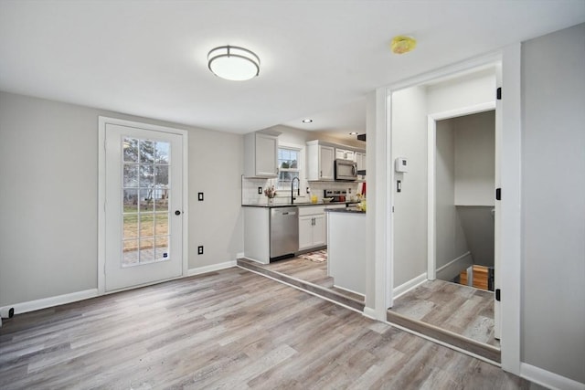 kitchen with appliances with stainless steel finishes, tasteful backsplash, sink, light hardwood / wood-style flooring, and white cabinets