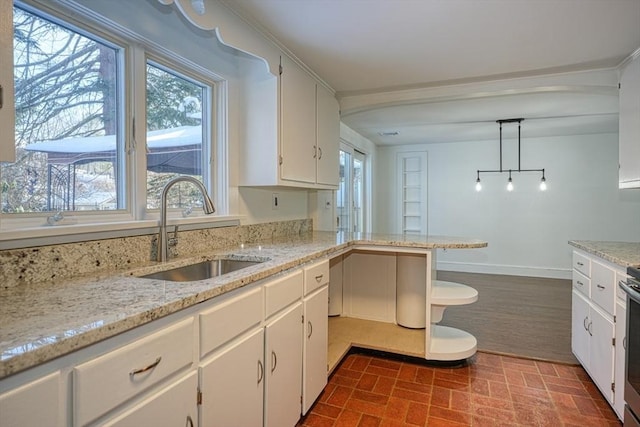 kitchen with sink, white cabinetry, decorative light fixtures, kitchen peninsula, and light stone countertops